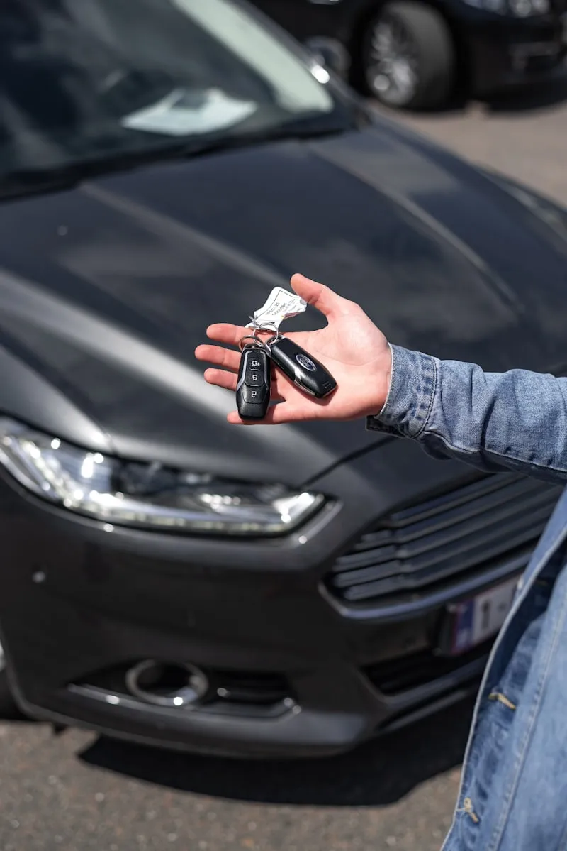 A hand holding a car key and fob.