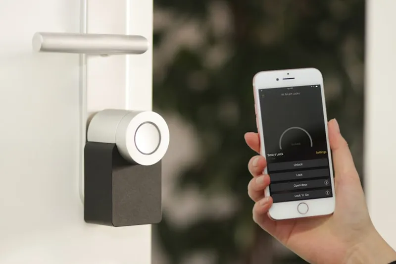 A smart lock on a front door being unlocked from a phone app.